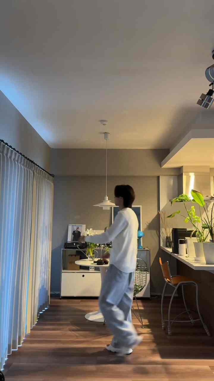 ホワイトとブラウンのトーンでまとめられたモダンなキッチン兼ダイニング空間、中央に丸テーブルとディスプレイラックが配置された印象的なインテリア