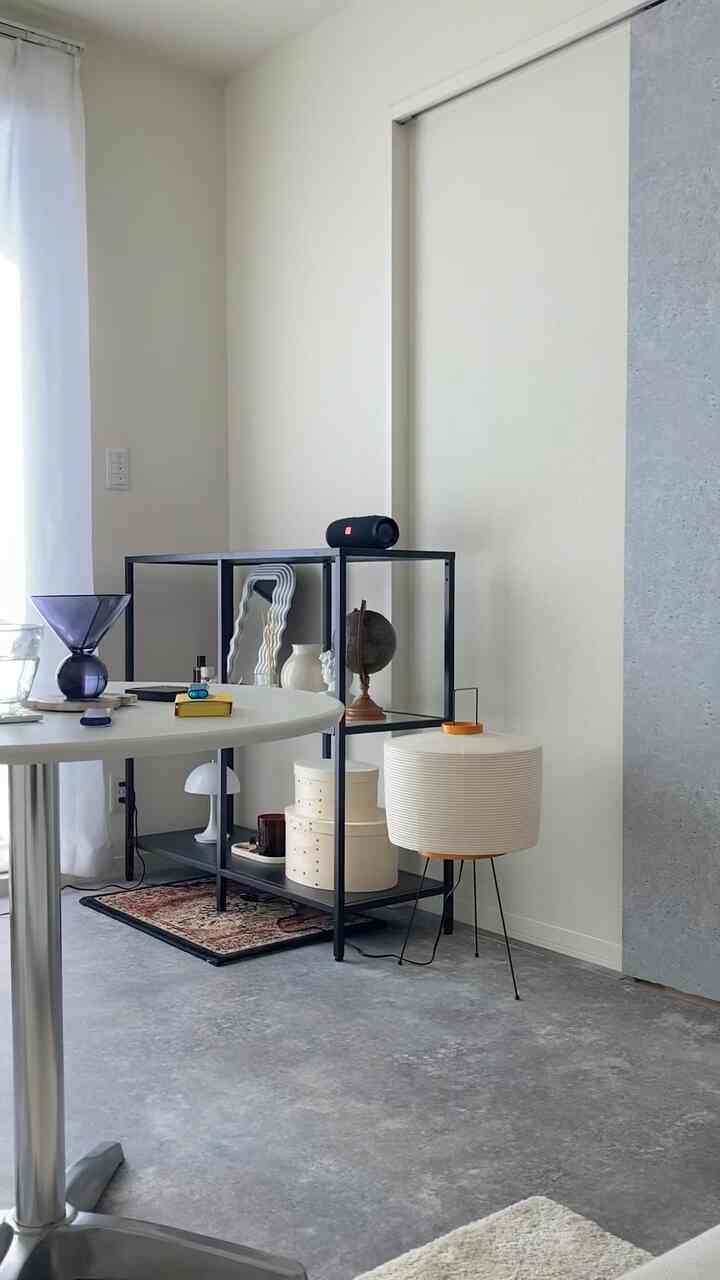 ホワイトとグレーのモノトーン1LDKリビング、シンプルなデスク、サイドテーブル、フロアランプが配置された印象的な空間