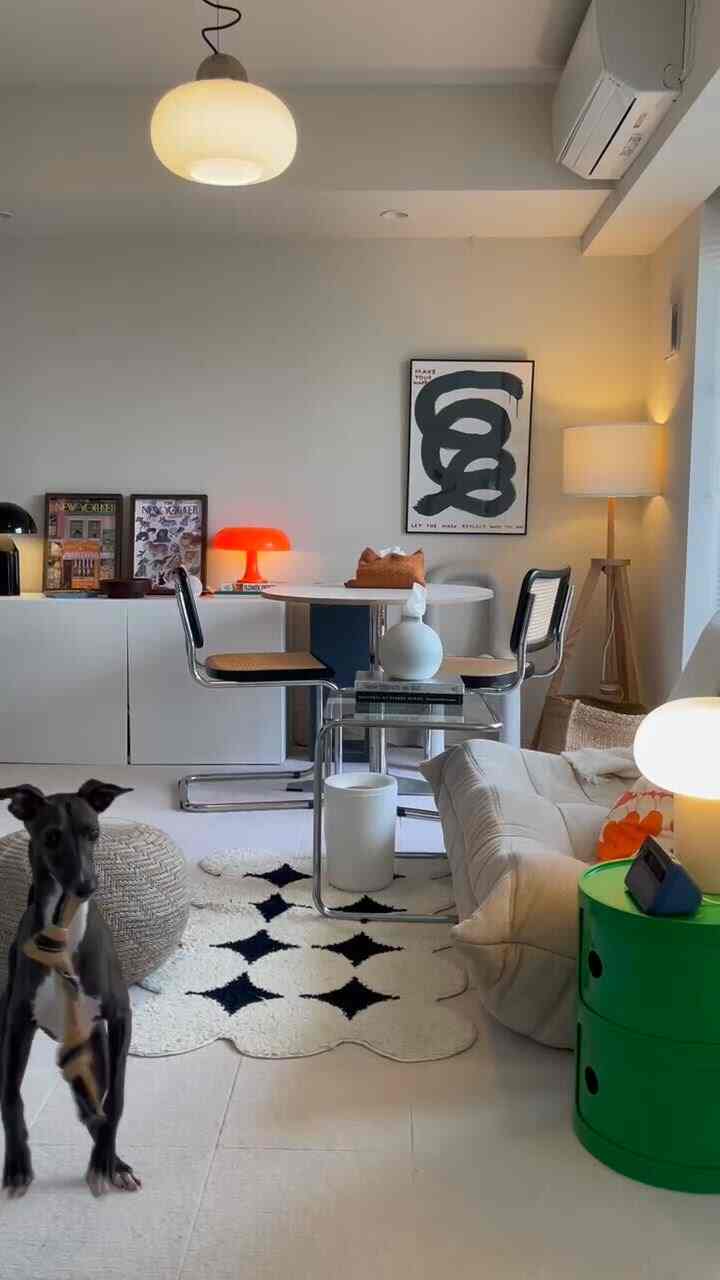 A white-toned living room with mid-century modern style two-person furniture, featuring a dog and cozy atmosphere