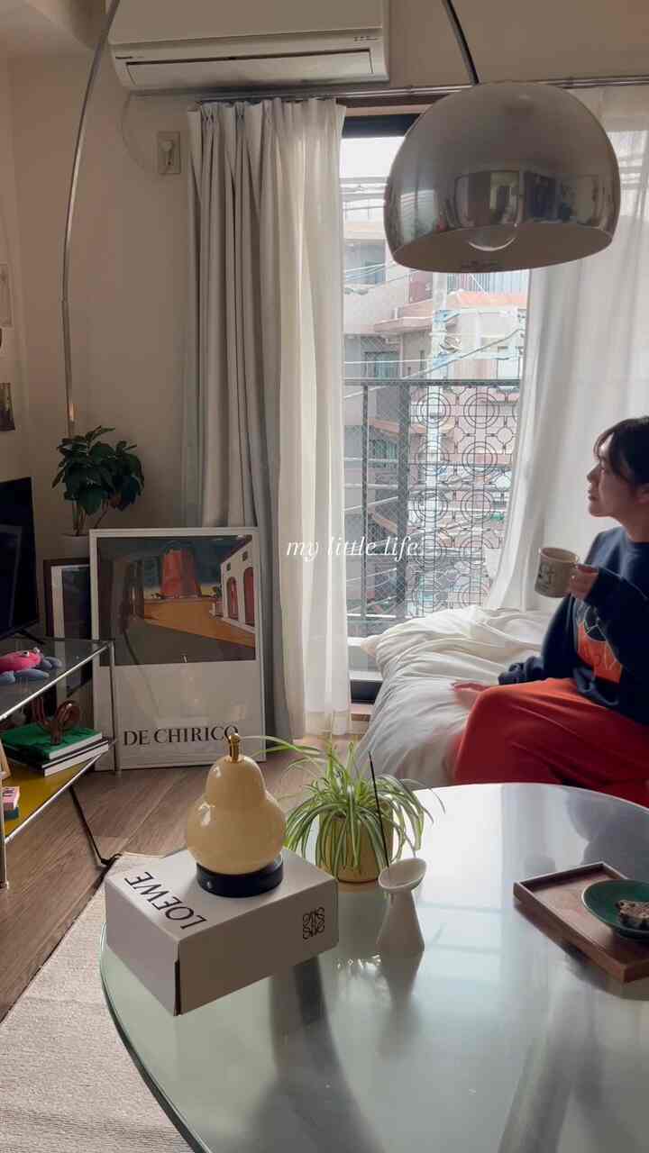 白と木目調が調和した8畳の寝室に、ベッドとサイドテーブル、アーチ型のフロアランプが配置された落ち着いた一人暮らしの空間