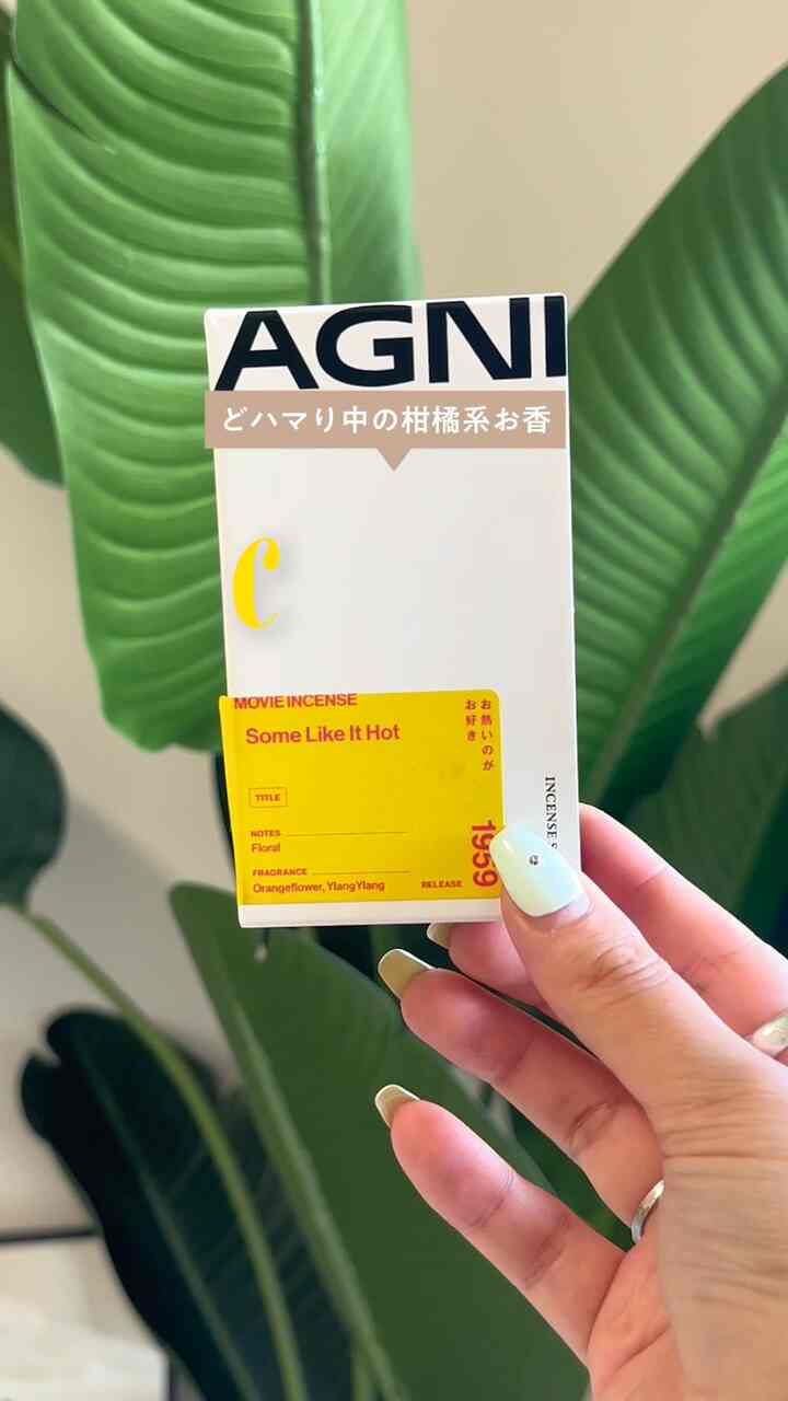 緑の植物が背景にあり、手に白と黄色の香りの箱を持つ寝室の雰囲気あるインテリア