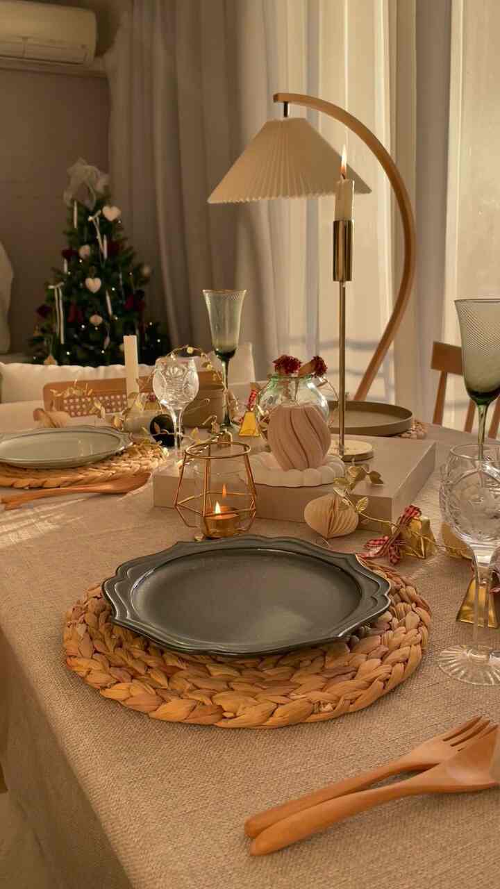 ベージュとナチュラルな色調のダイニングルーム、テーブルにはゴールドの装飾とキャンドルが配置された雰囲気のあるインテリア