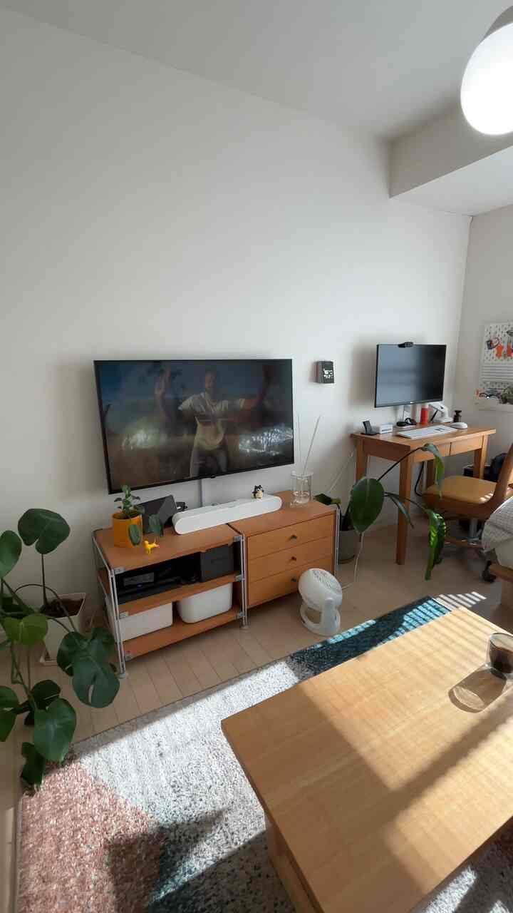 Bright natural wood tone 1K living room for a single household with desk, TV stand, and coffee table in a clean space