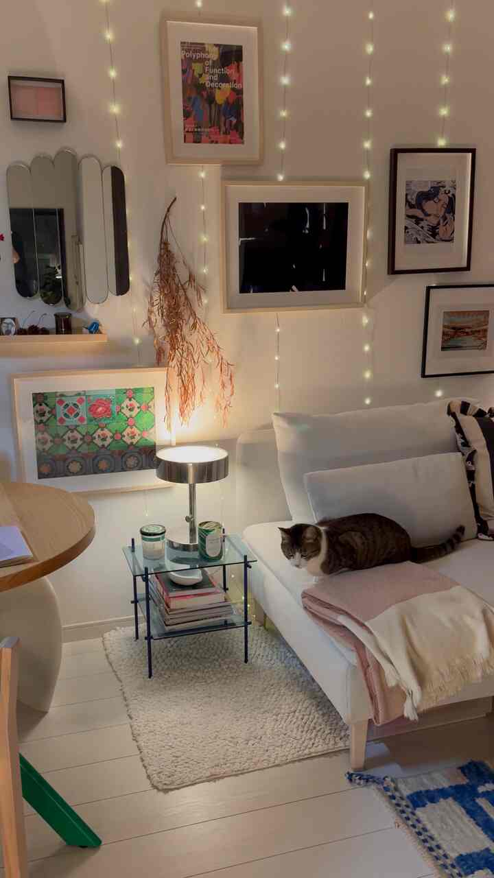 白とナチュラルカラーのリビング、猫とともにソファとテーブルランプが配置された、落ち着いた雰囲気のあるインテリア