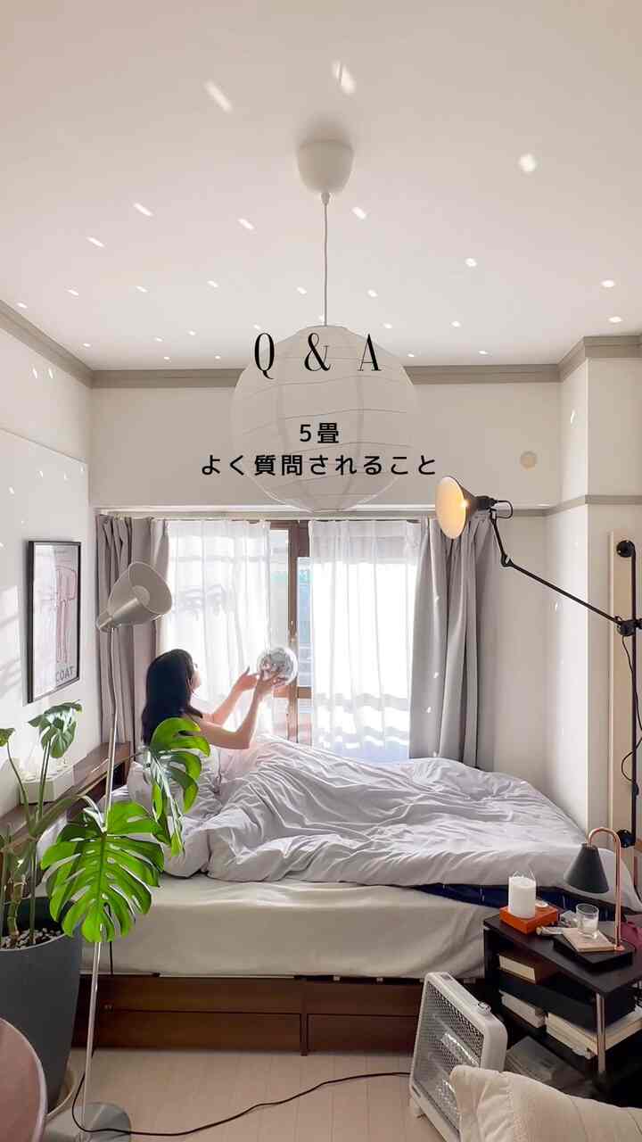 白と茶色のトーンの5畳の寝室、大きなベッドと植物が配置され、落ち着いて広々とした雰囲気のインテリア