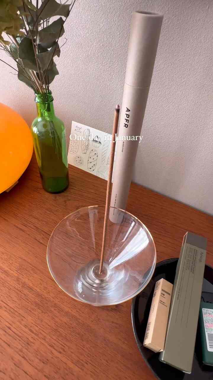 Natural interior space with a brown wood-tone table featuring a transparent incense holder and green glass bottle