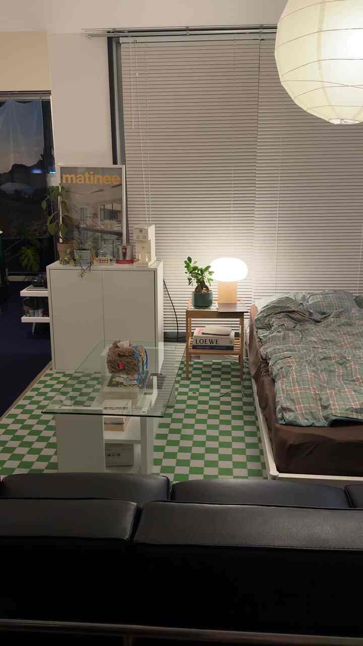 白と緑のトーンのワンルーム寝室、ソファとナイトテーブル、コーヒーテーブルが配置された雰囲気ある空間