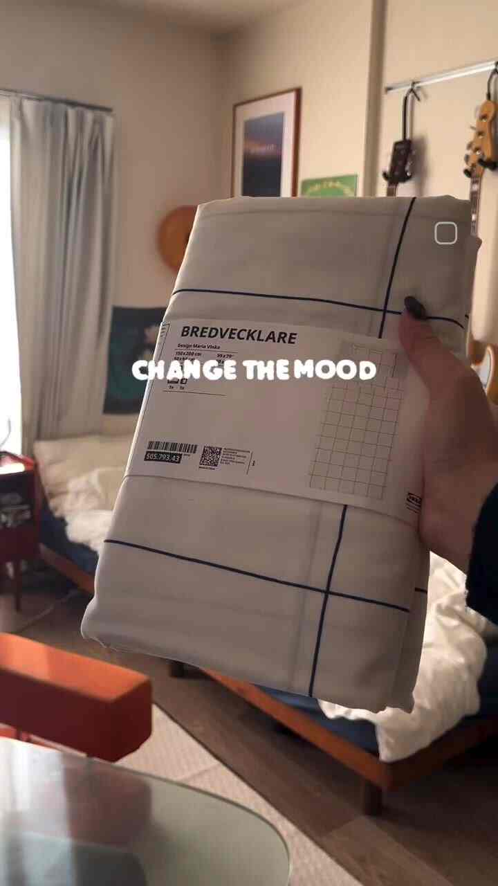 白と木目調の8畳寝室、ミッドセンチュリーモダンスタイルのベッドとクッションが配置された温かみのあるインテリア