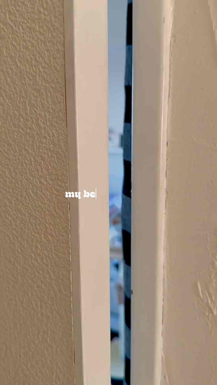 白とシルバーのトーンの寝室、ベッドやラグ、カーテン、壁に設置されたイケアの棚があるモダンな空間