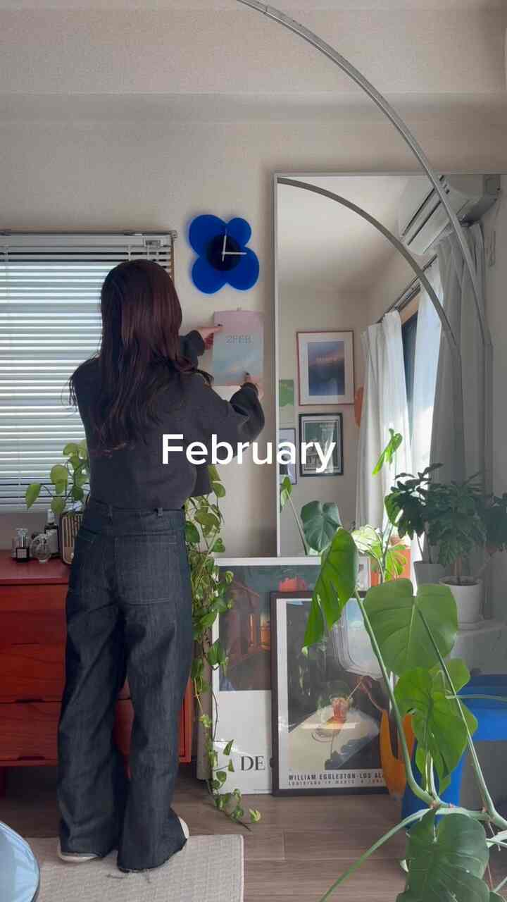 An 8-tatami room in white and red tones featuring mid-century modern furniture, large mirror, and several green plants in a cozy single household space