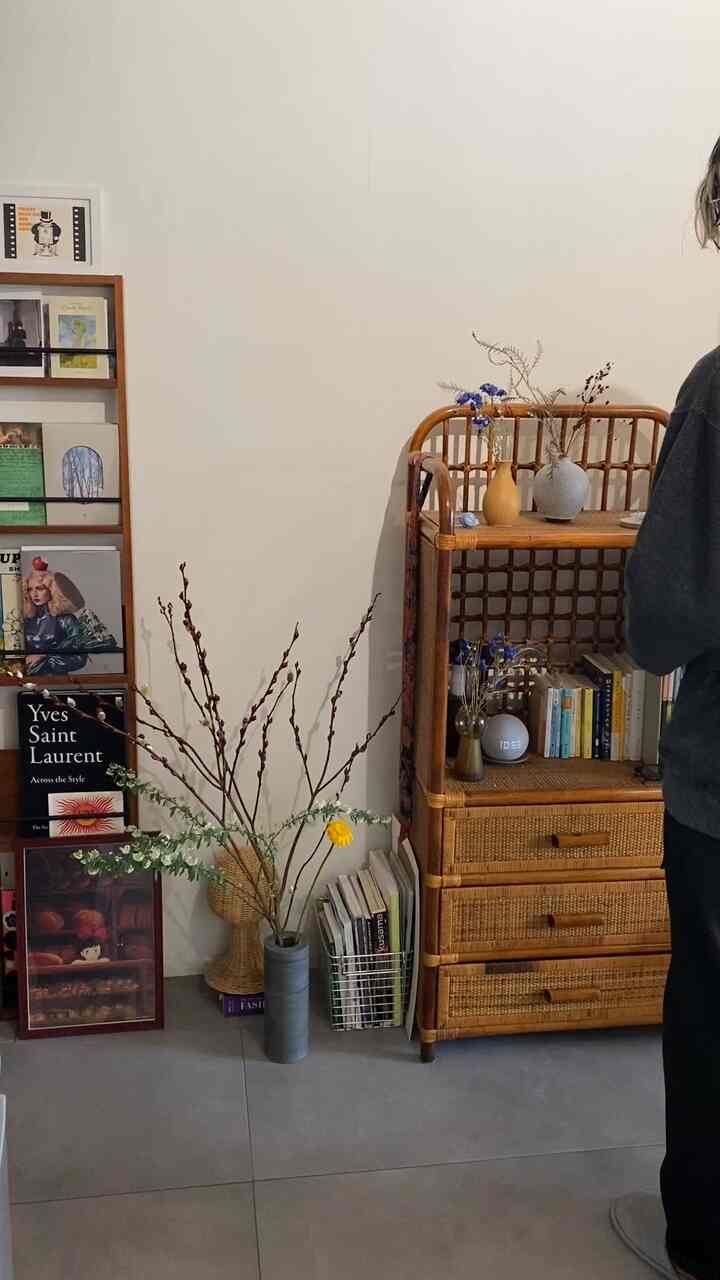 Natural-toned studio living room featuring rattan furniture and bookshelves with a calm atmosphere