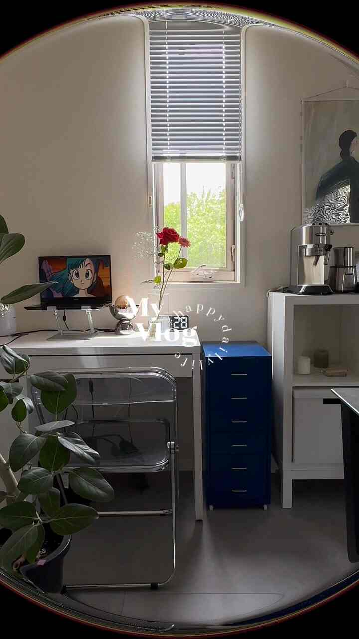 Minimal and modern small home office space in white and gray tones, featuring a transparent chair and blue drawer cabinet