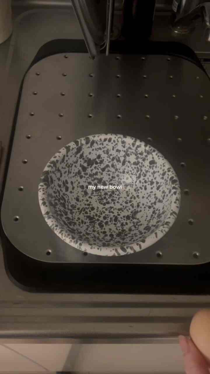 Monotone kitchen featuring a black and white speckled bowl centered on a metal surface, presenting a simple atmosphere