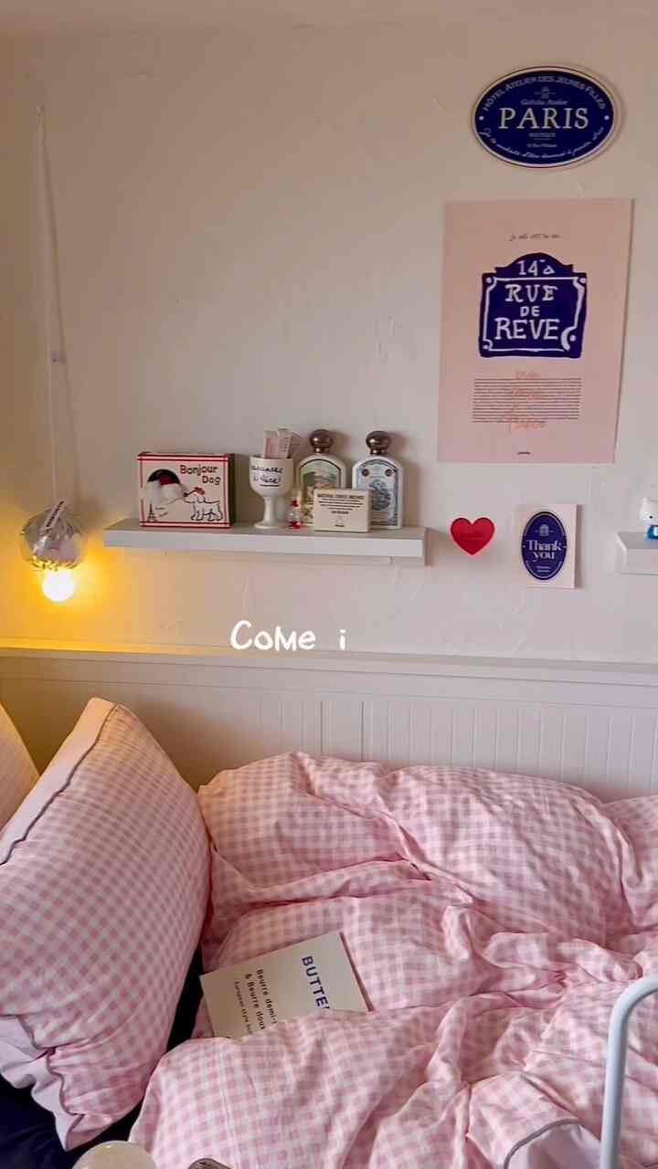 ピンクとホワイトのトーンの寝室、ピンクのギンガム柄寝具と壁照明が配置された印象的な空間