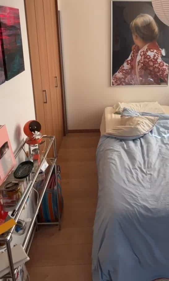 Modern cozy bedroom with white walls and brown wood tone flooring, featuring a blue bedspread