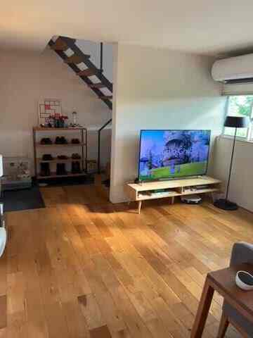 A Nordic style living room with white walls and wood tone floor, featuring a TV stand and floor lamp creating a cozy atmosphere