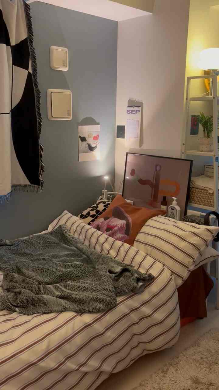 ベージュとホワイトのトーンの寝室、ストライプ柄の布団カバーとレトロスタイルのクッションが配置された雰囲気のあるインテリア