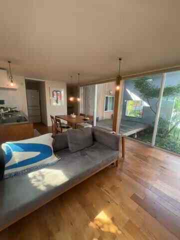Natural-toned Nordic living room featuring large windows, gray sofa, and wooden flooring creating a cozy atmosphere