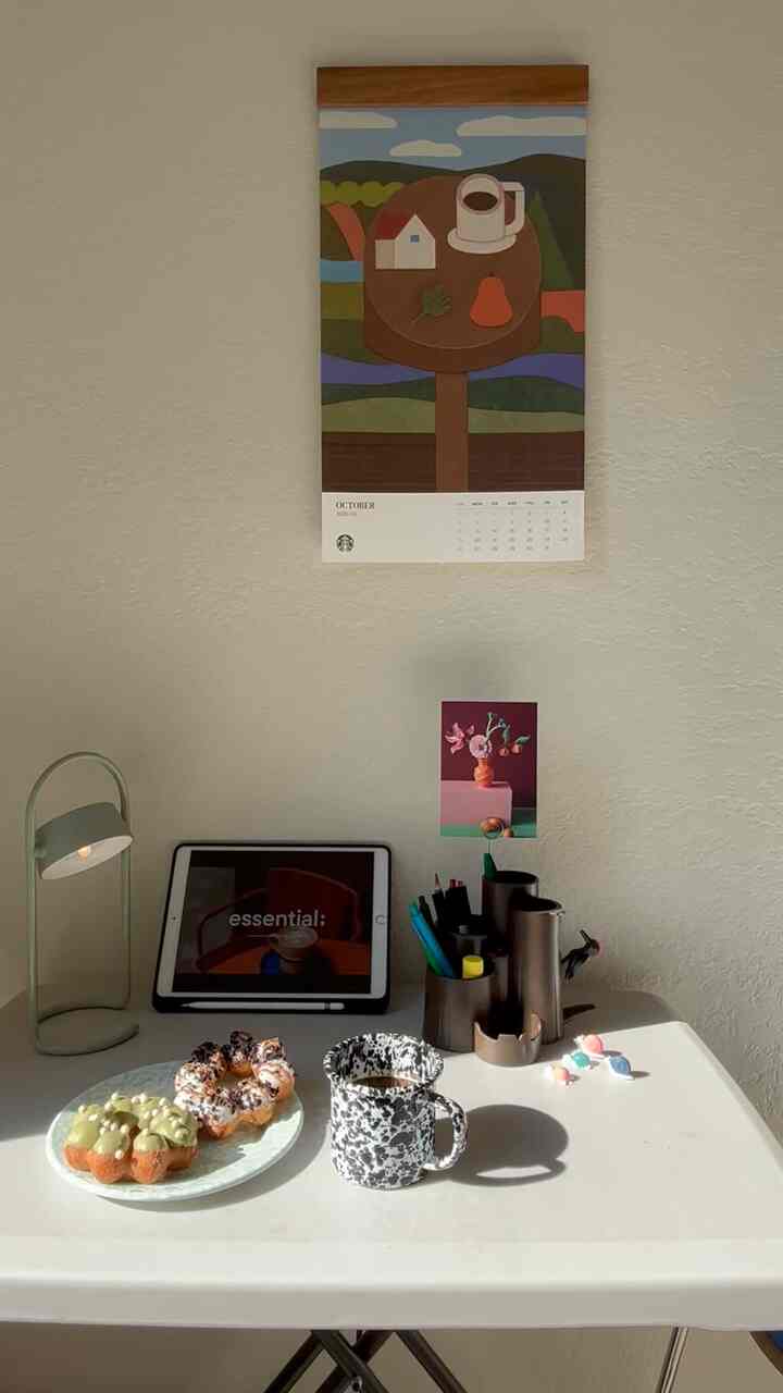 White table and green table lamp in a home office space featuring coffee cup and donuts on a cozy workspace
