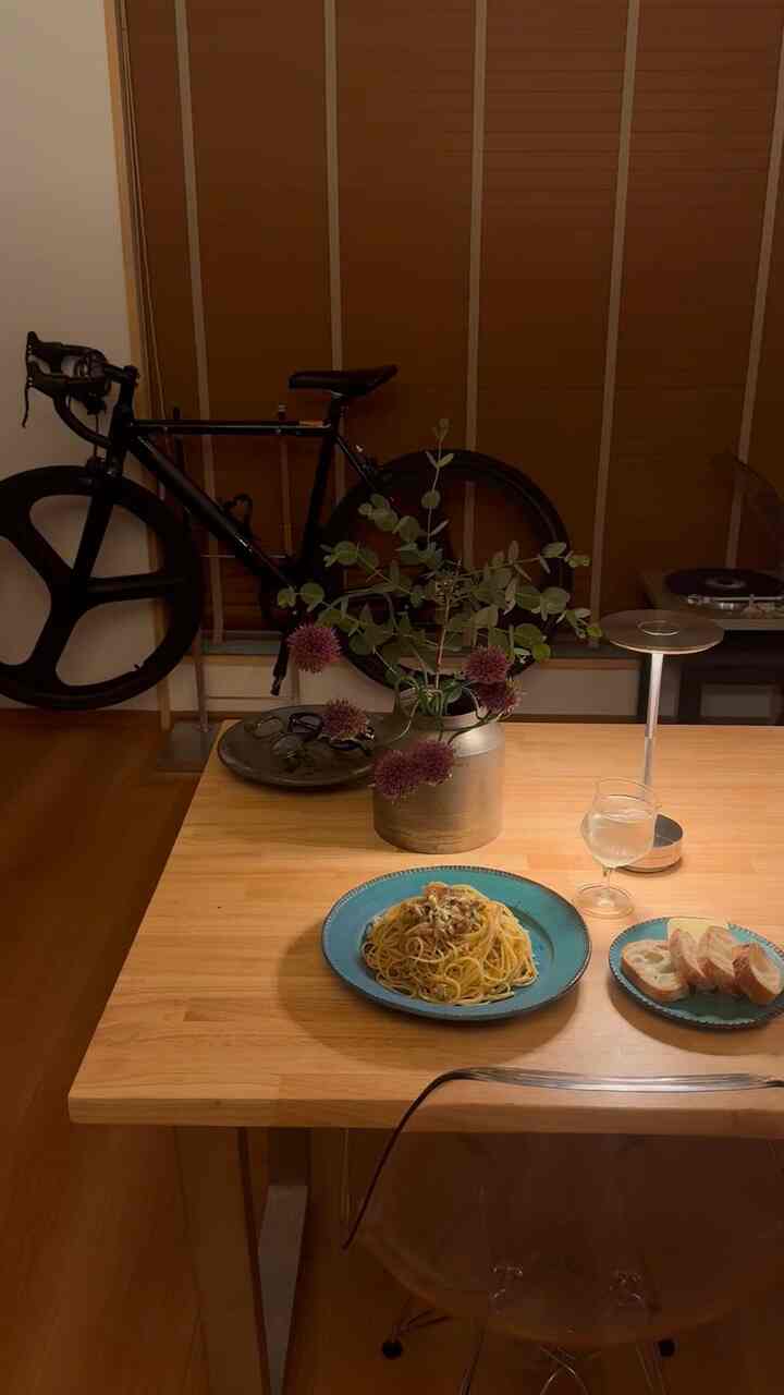 暖かみのあるブラウンの木目調が特徴的な1LDKのダイニングスペース、中央には花瓶と食事が置かれた雰囲気のあるおうちカフェインテリア