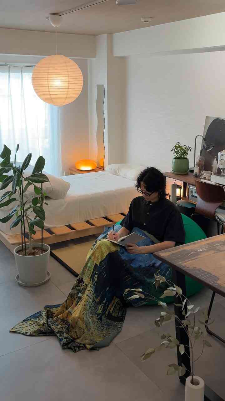 ナチュラルカラーのワンルーム、ベッド、ビーズクッション、植物が配置された落ち着いた雰囲気のインテリア