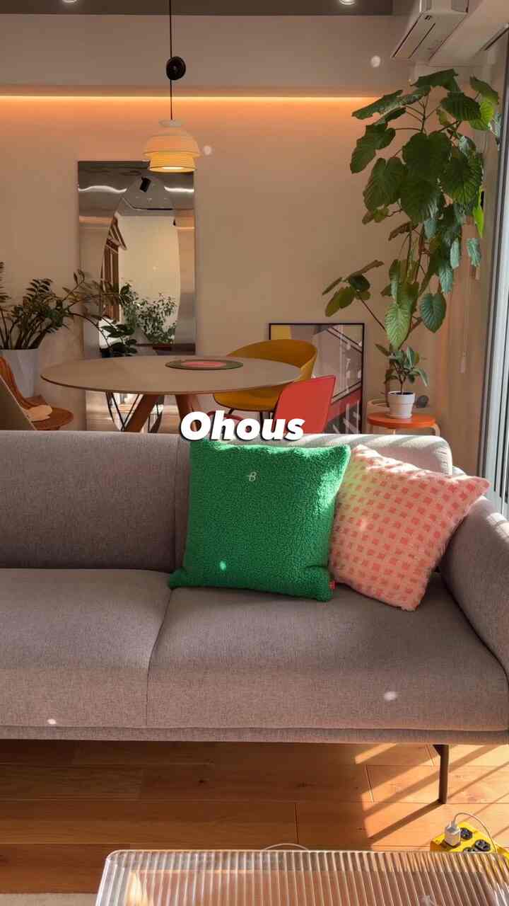 温かみのあるウッドトーンとナチュラルカラーのリビング、丸いダイニングテーブルとグレーのソファが配置された雰囲気のある空間