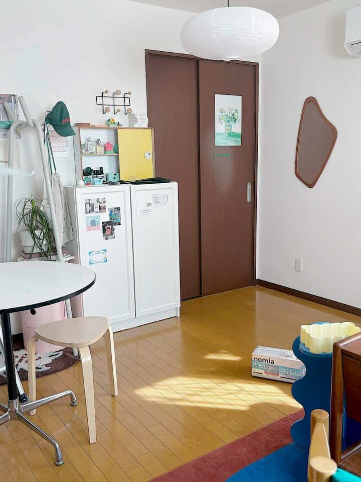 白と茶色の色調が調和したリビング、ラウンドテーブルとシンプルな椅子が配置されたミニマルでナチュラルな雰囲気のインテリア