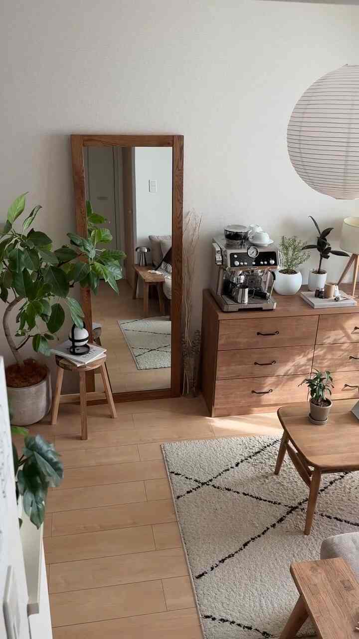 ナチュラルな木目調のリビング、植物や姿見、コーヒーマシンが配置された雰囲気のある空間