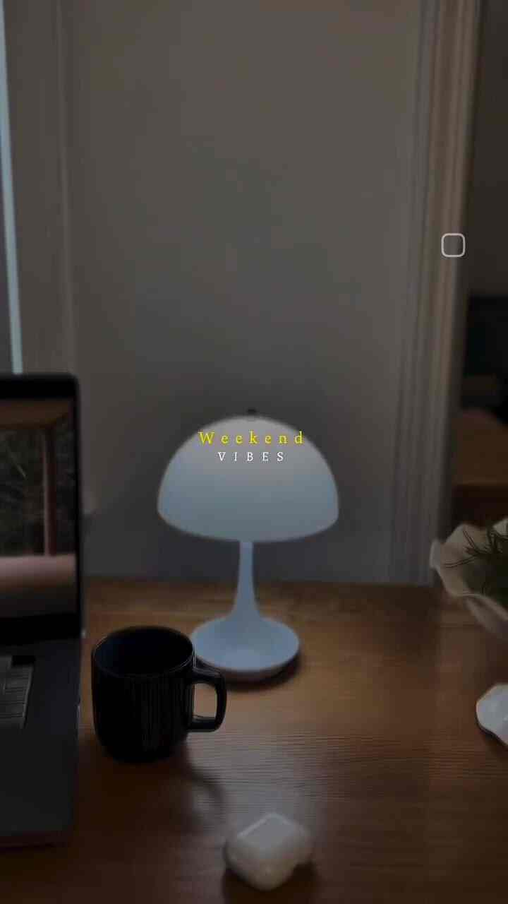 Cozy and calm home office with a brown wooden desk featuring a soft white table lamp illuminating the space