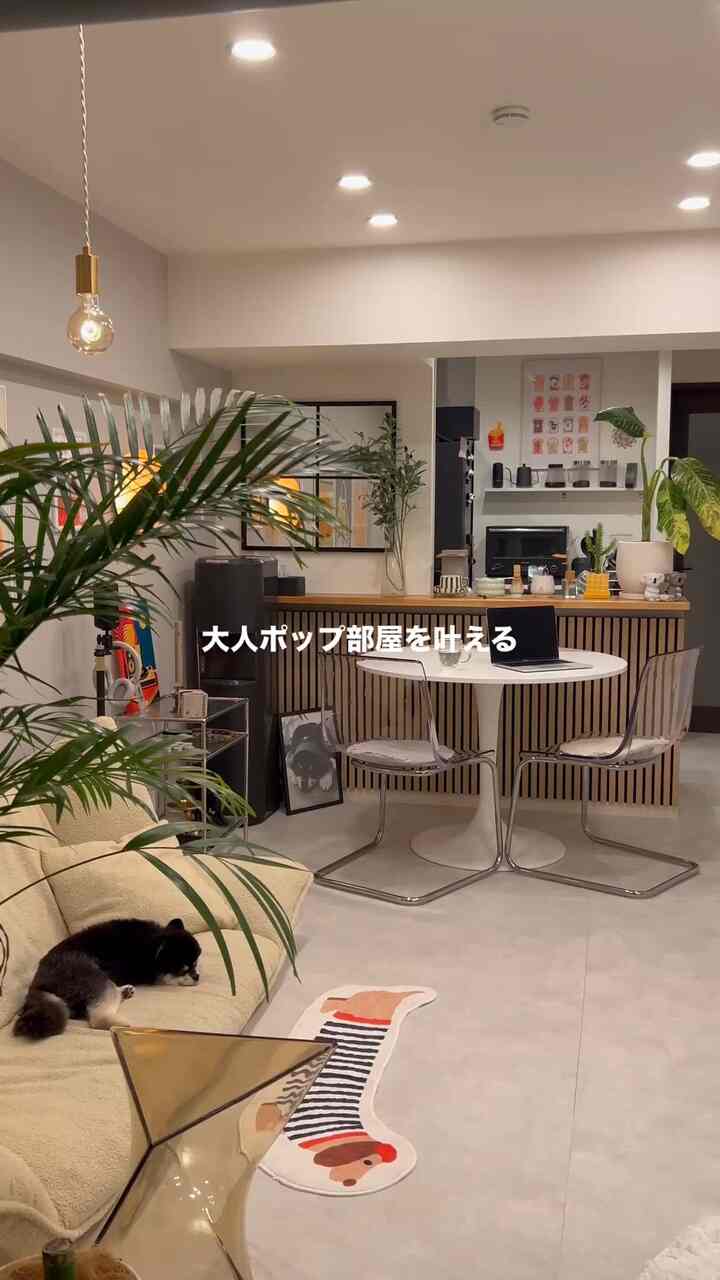 白とベージュの色調のリビング、ベージュのソファと丸いダイニングテーブル、透明な椅子が配置された印象的で居心地の良いインテリア