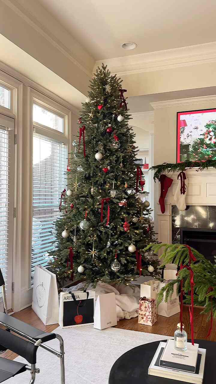 White-walled living room featuring a decorated Christmas tree with red ornaments and stockings, creating a cozy festive atmosphere