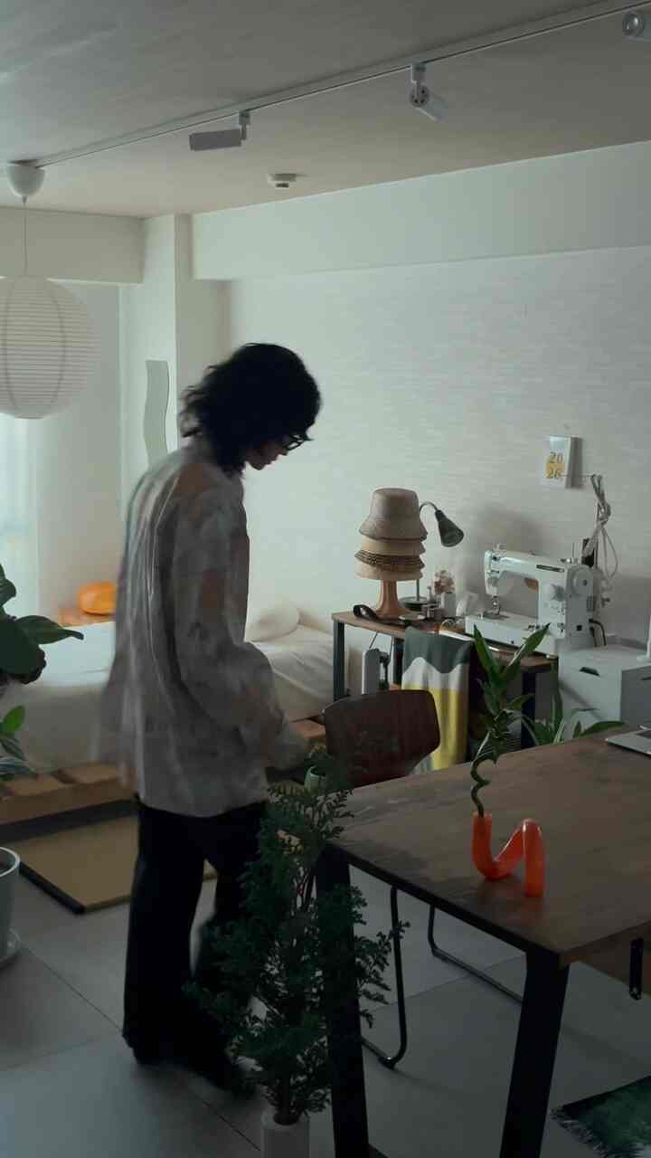 ナチュラルカラーのワンルーム寝室兼作業スペース、間接照明と植物、木製家具が調和した雰囲気のあるインテリア