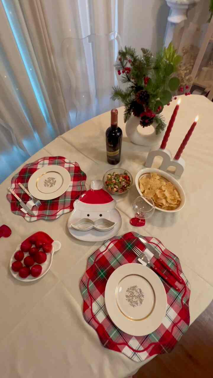 Red and beige toned dining room featuring Christmas decorated vase and candles on a cozy dining table setup