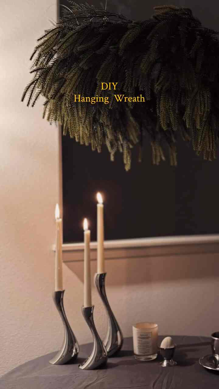 Gray table with silver candle holders in a living room, green DIY hanging garland on ceiling creates cozy atmosphere