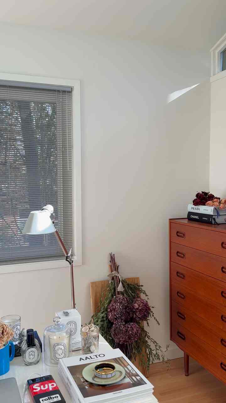 White and brown toned home office featuring desk with table lamp and candles, creating a cozy atmosphere