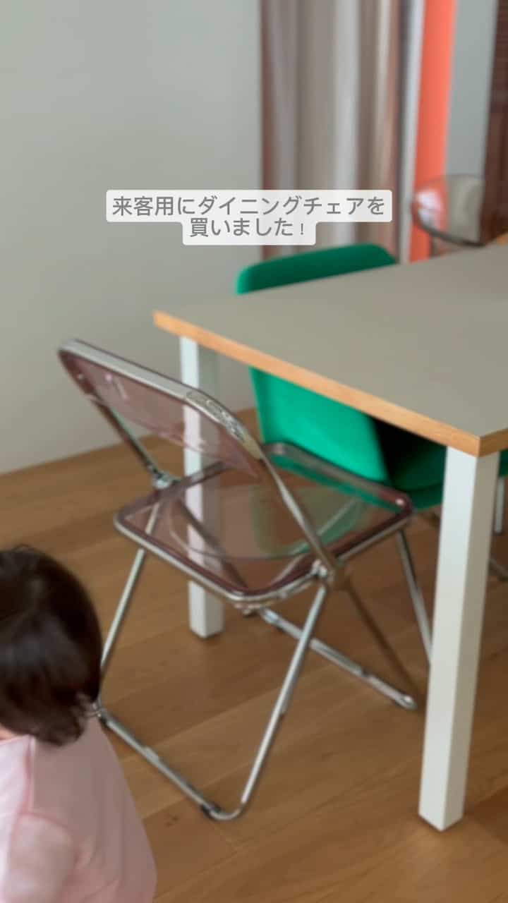 白い壁と木目調の床のダイニング、透明な折りたたみ椅子と緑のダイニングチェアが配置された子供と暮らす空間