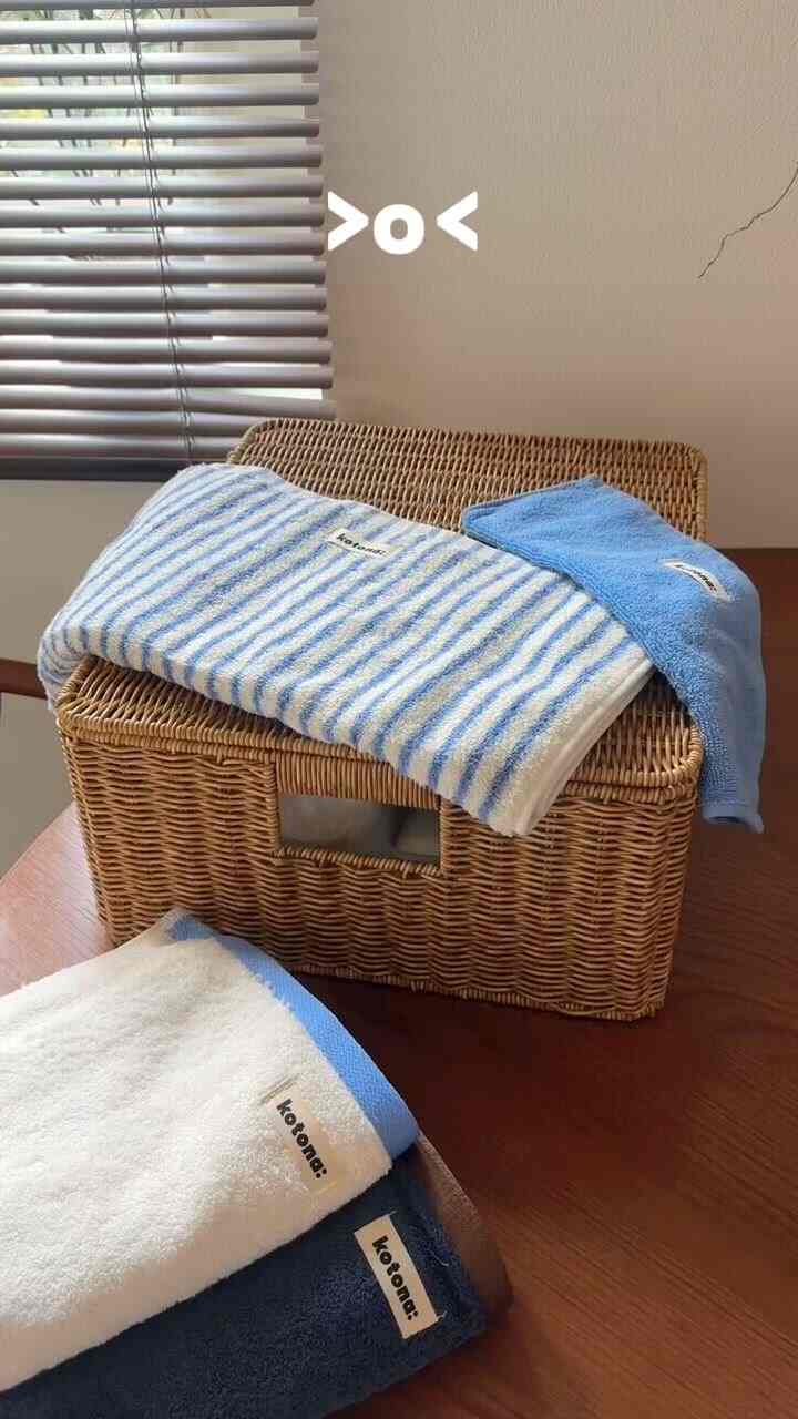 自然なベージュのウッドトーンの収納バスケットと白と青のタオルが置かれた印象的なインテリア