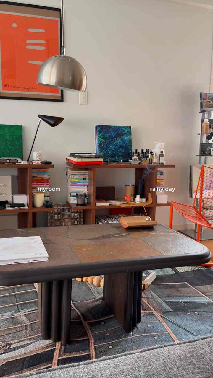 Mid-Century Modern studio apartment with brown wood tones and orange accents, featuring a coffee table and wall art in a cozy atmosphere