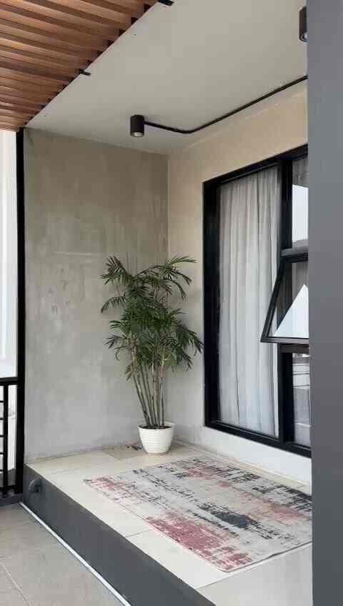 A beige and gray-toned balcony space featuring a large green plant, creating a modern and natural atmosphere.