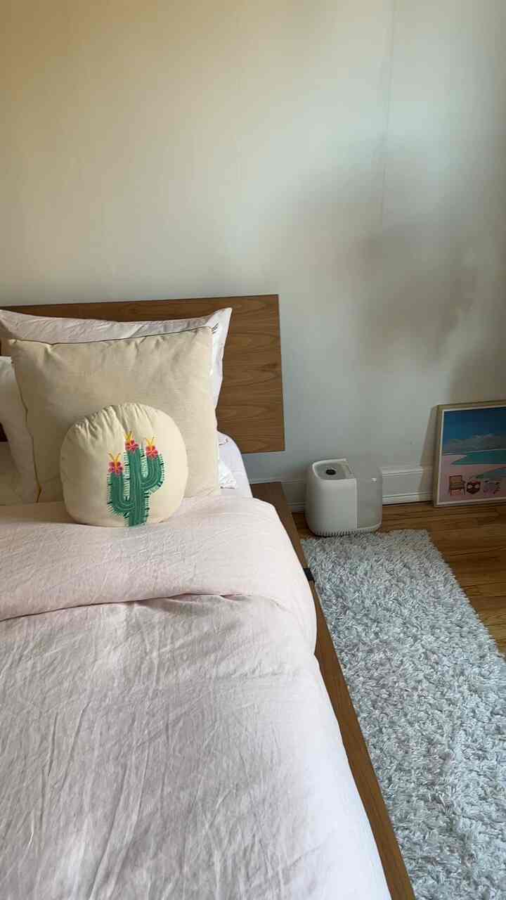 Natural modern bedroom corner featuring soft wood tones, white walls, and pastel bedding with a serene atmosphere
