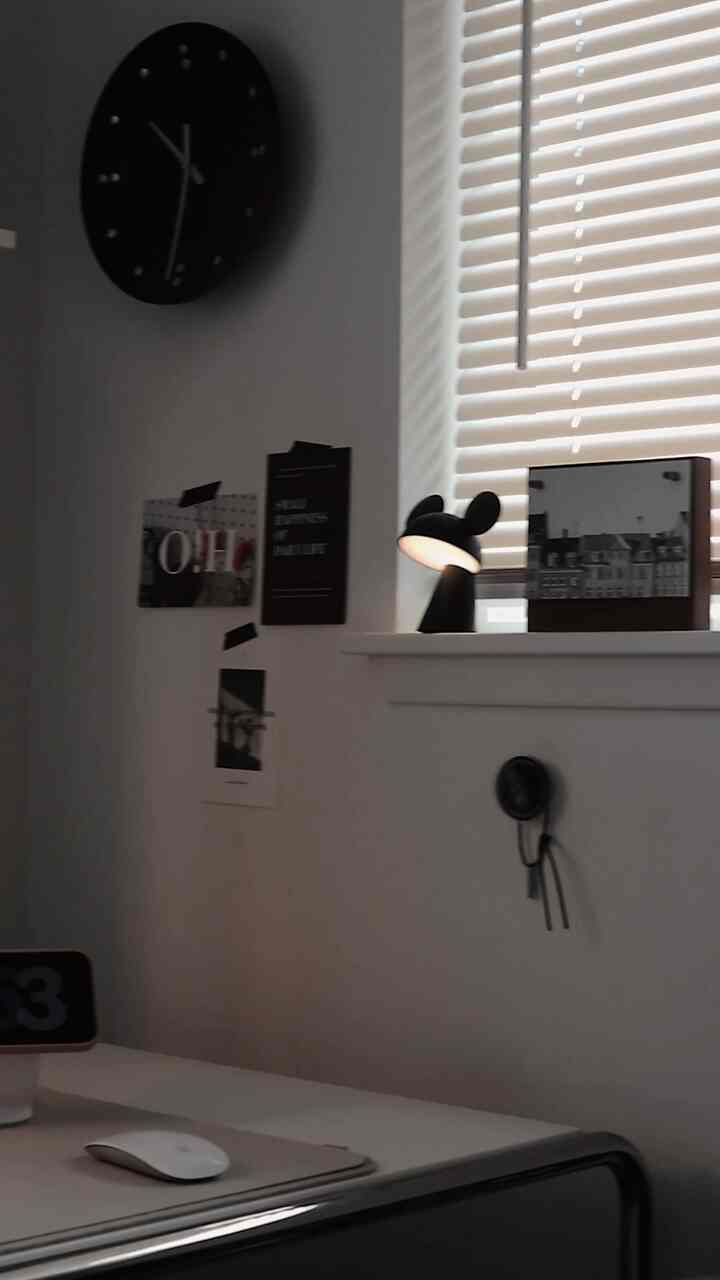 White and black toned home office featuring an iMac and table lamp with a clean, modern workspace