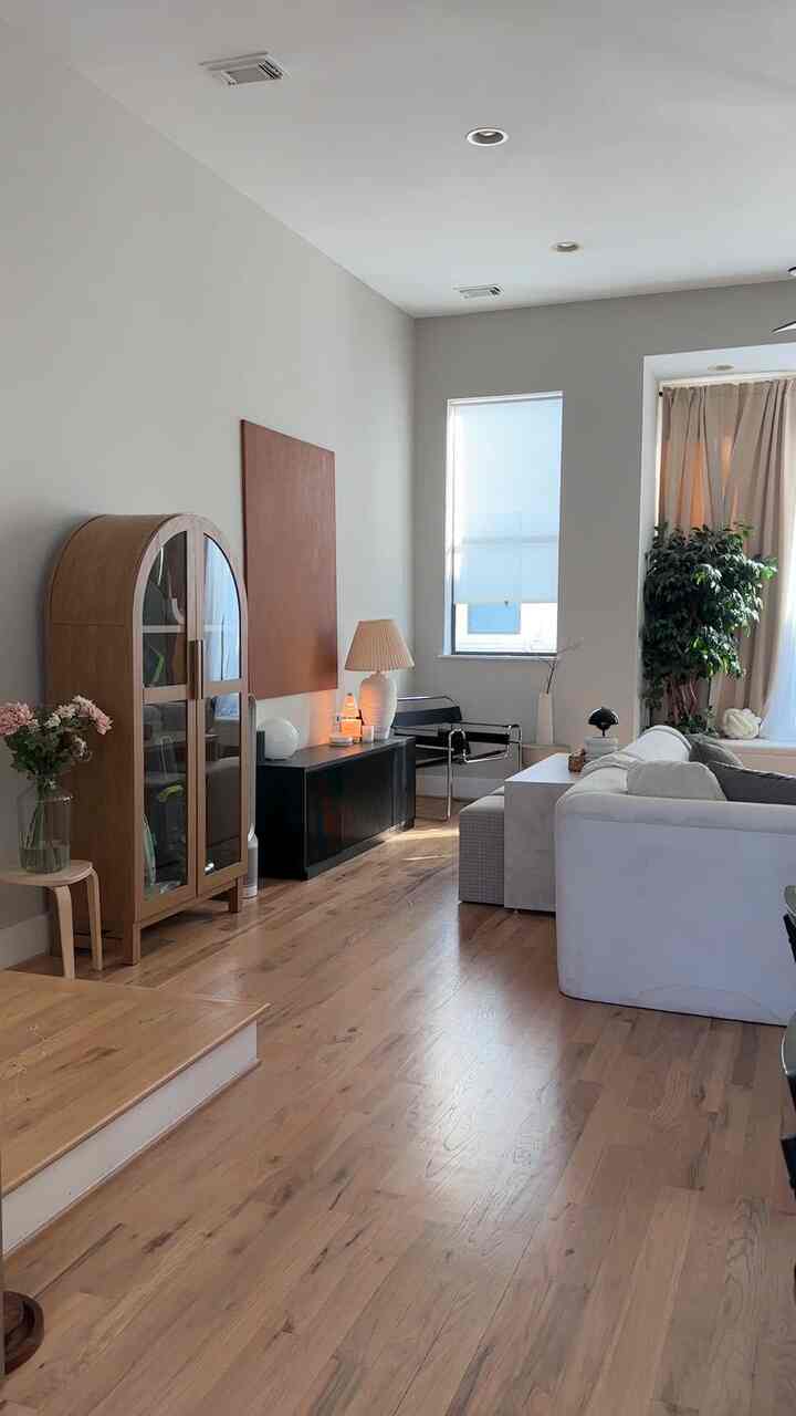 Modern living room in white and brown tones featuring a sofa and wooden furniture with warm natural ambiance