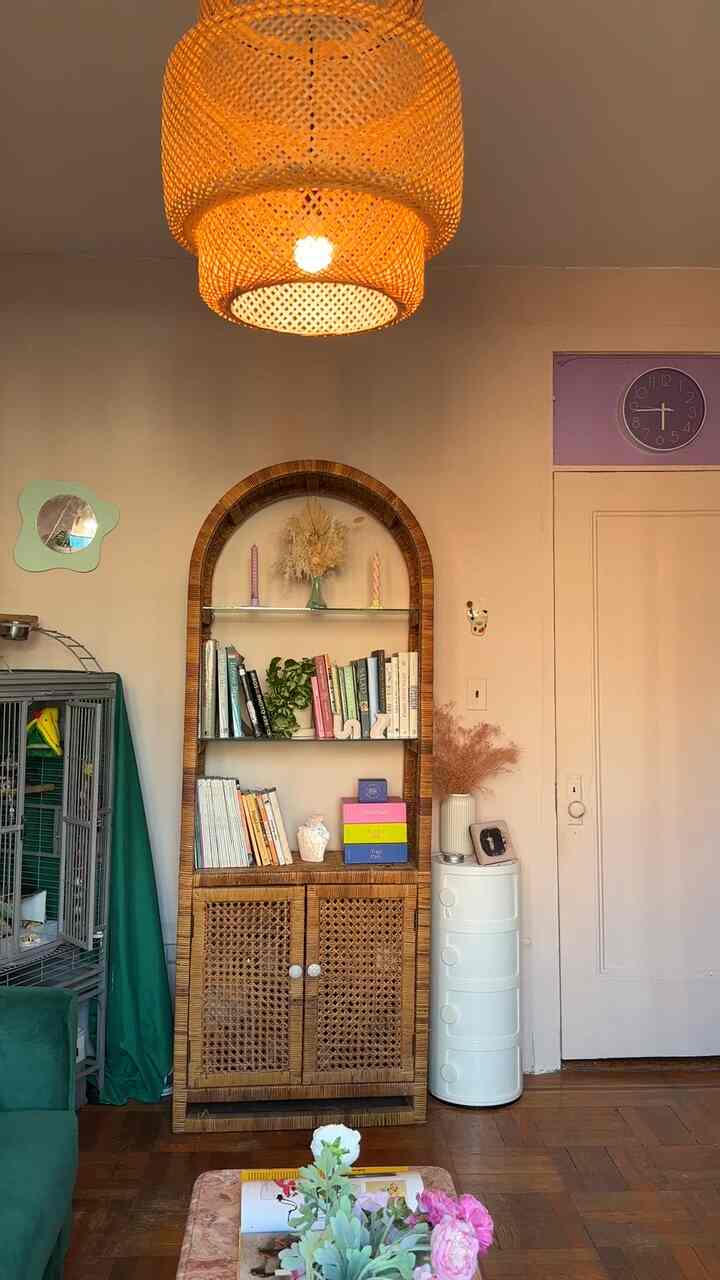 Warm wood-toned living room featuring rattan bookshelf and pendant light with bohemian style accents