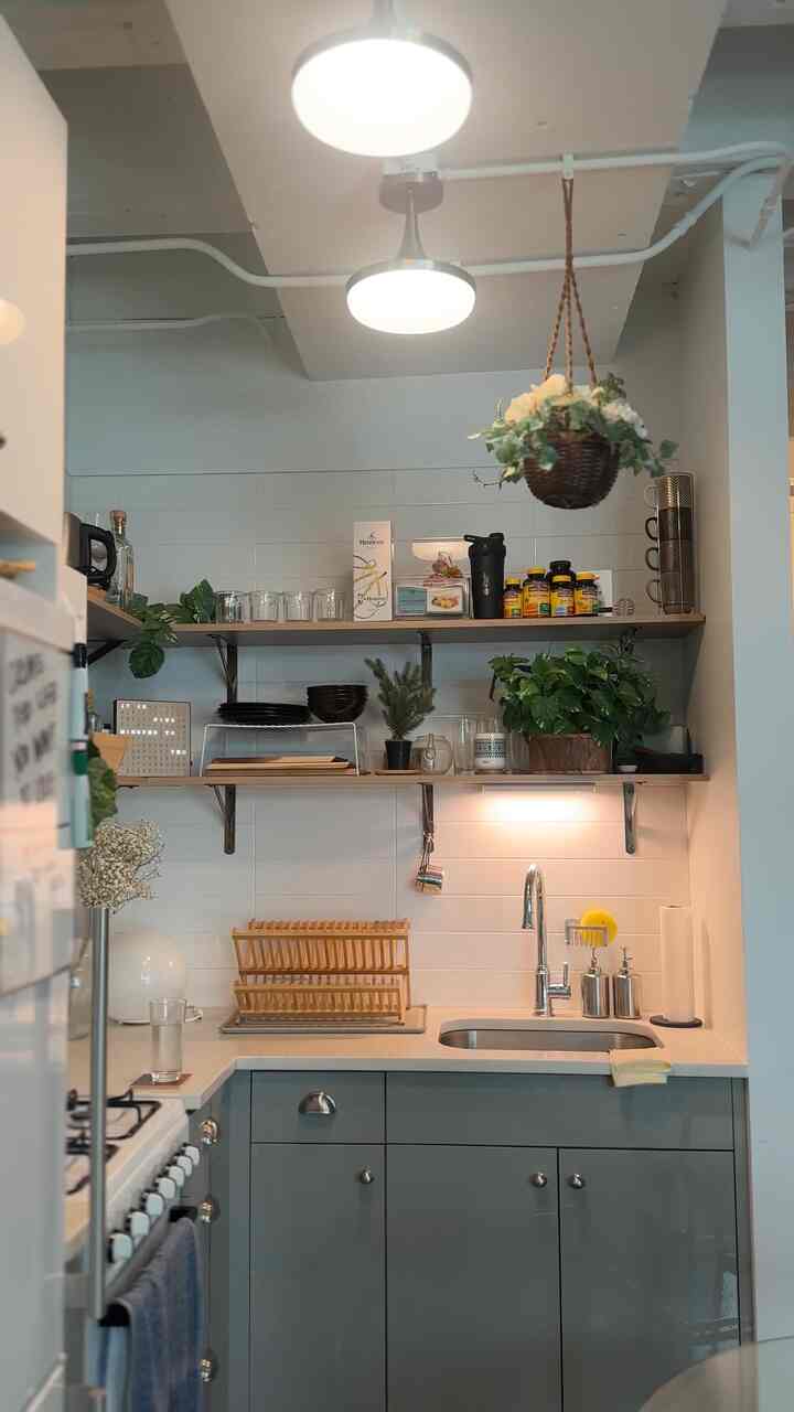 A cozy open shelf kitchen featuring white tiles and natural wood tones with green plants