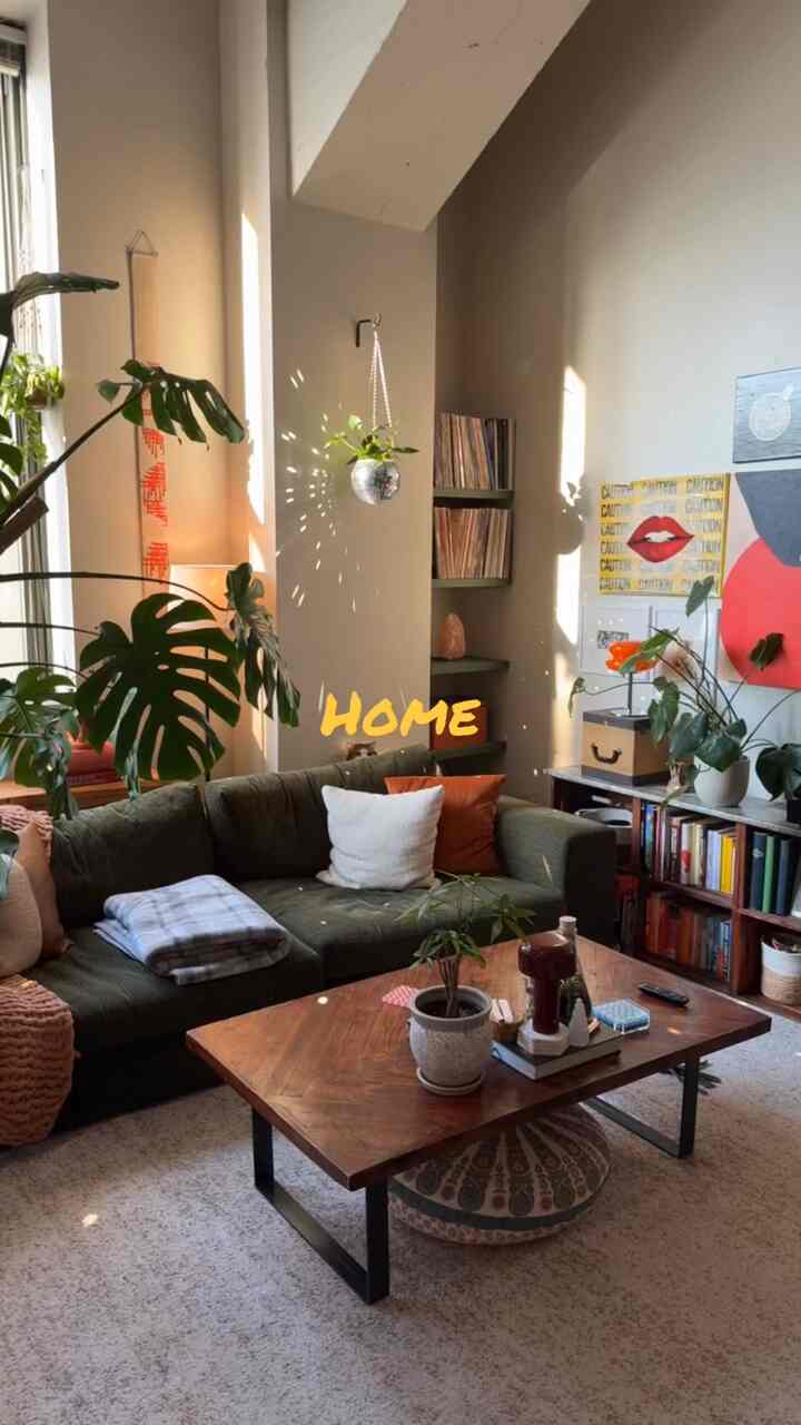 Natural modern living room in brown and green tones, featuring a large sofa, wooden coffee table, various plants, and wall decor creating a cozy atmosphere