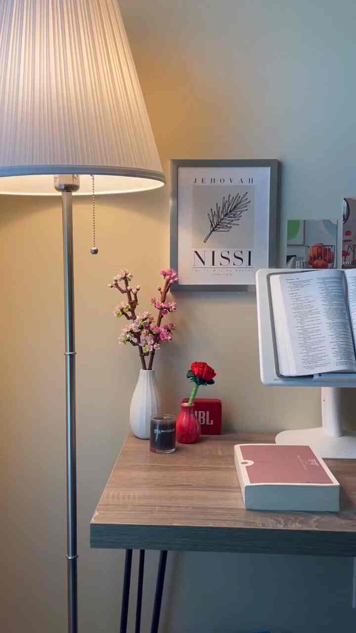 Bright toned home office space featuring a simple wooden desk with reading book, candle, and floor lamp, conveying a calm atmosphere