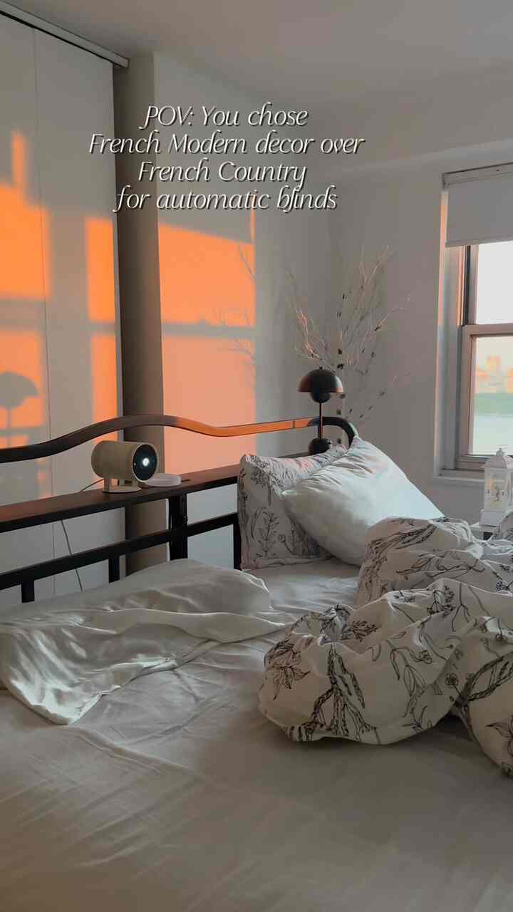 White and wood tone bedroom featuring floral bedding and automated blinds with warm natural sunlight creating a cozy atmosphere