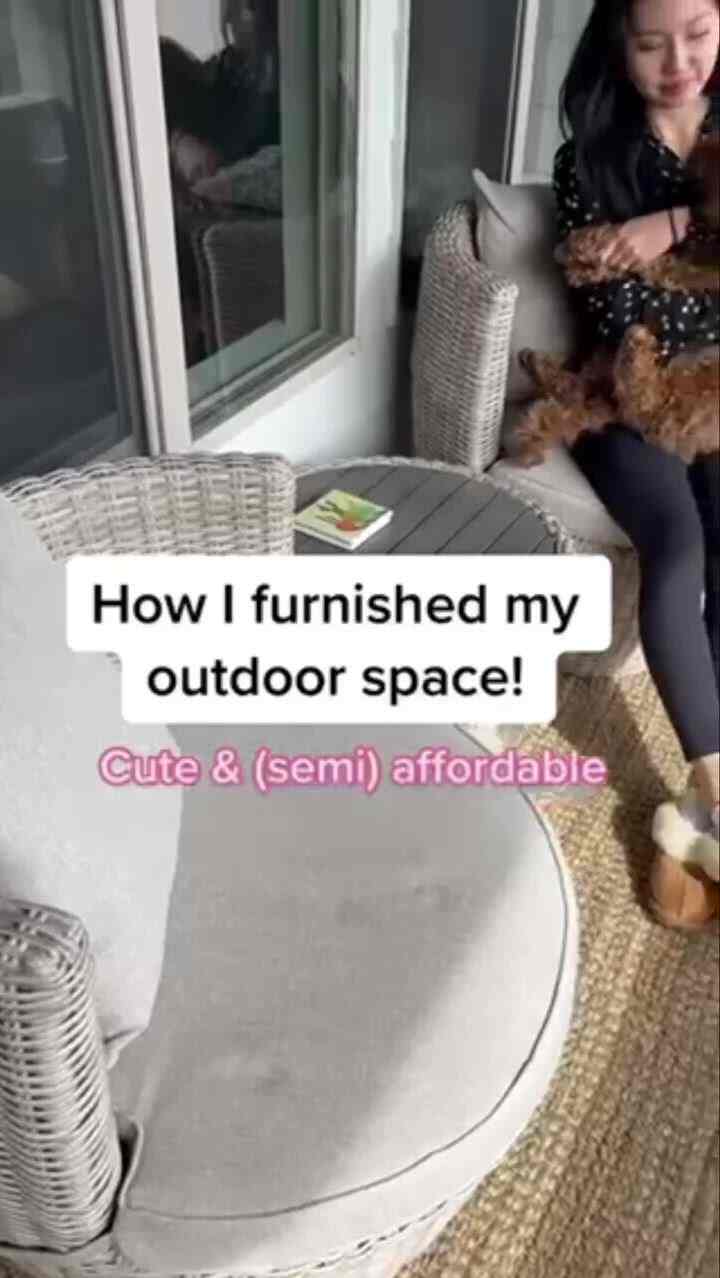 Brown and gray toned balcony featuring rattan outdoor chairs and table, with a cozy atmosphere and pet dog companionship