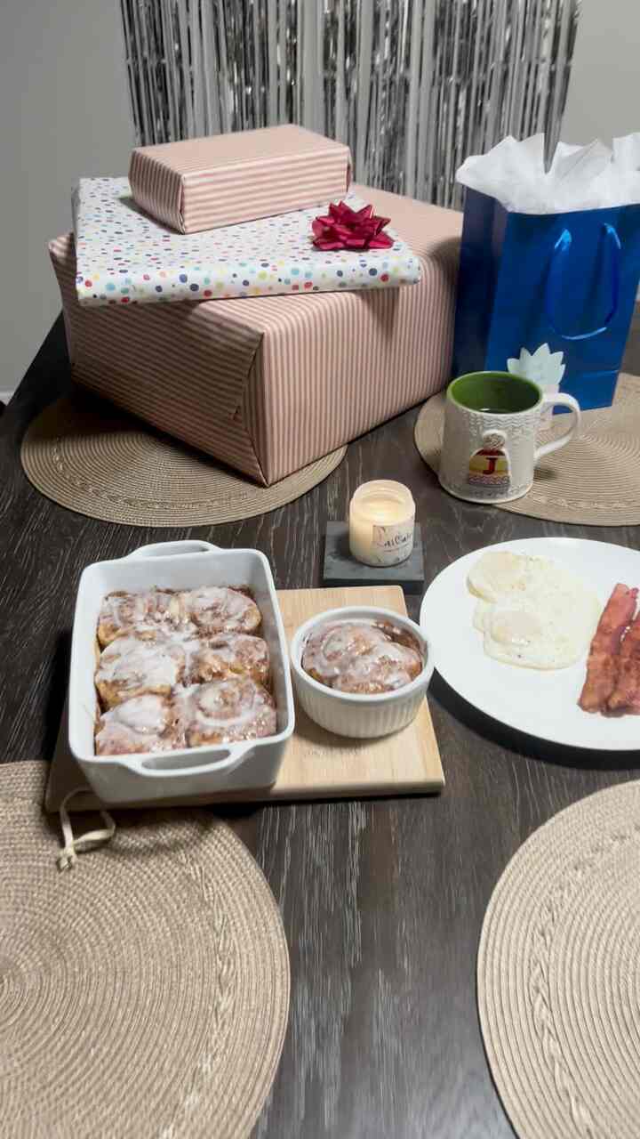 Dark wood dining table with beige placemats and wrapped presents, creating a cozy home party atmosphere