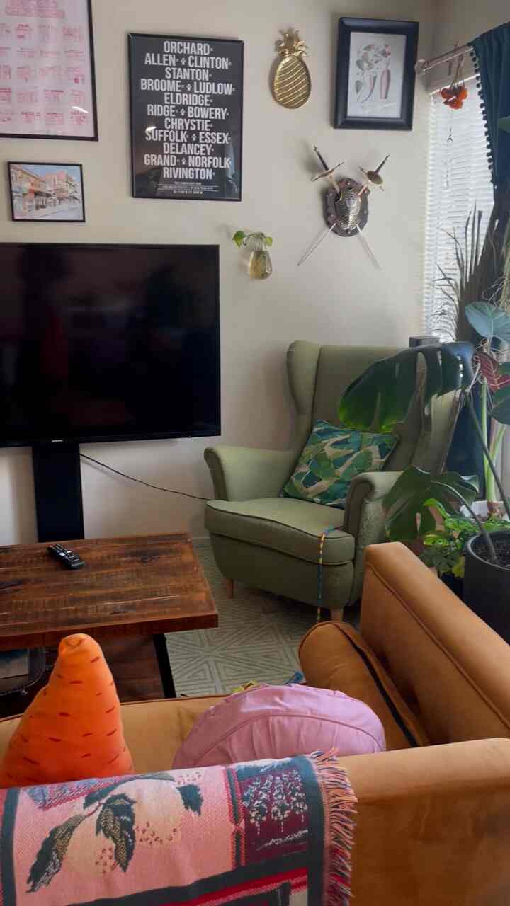 Bohemian living room with green armchair and brown sofa, colorful cushions and plants creating a cozy atmosphere